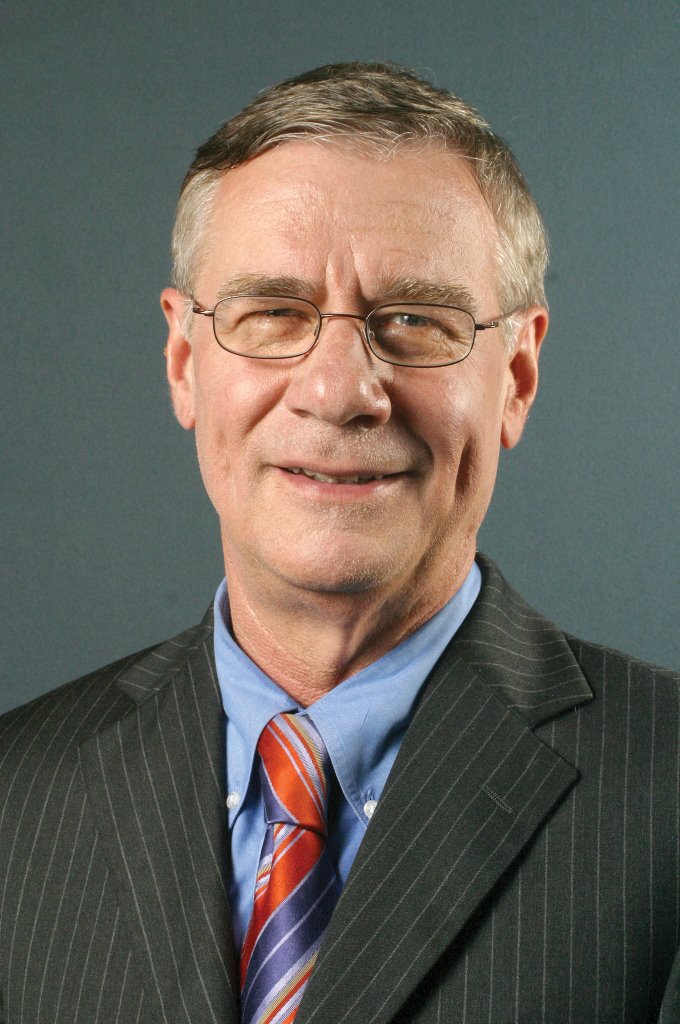 Picture of Patrick Michaels, White, grey hair, squity eyes, glasses, suit, and the devil's smile